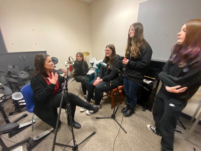 Group of four young people and their teacher using  microphones.  Podcasting Project